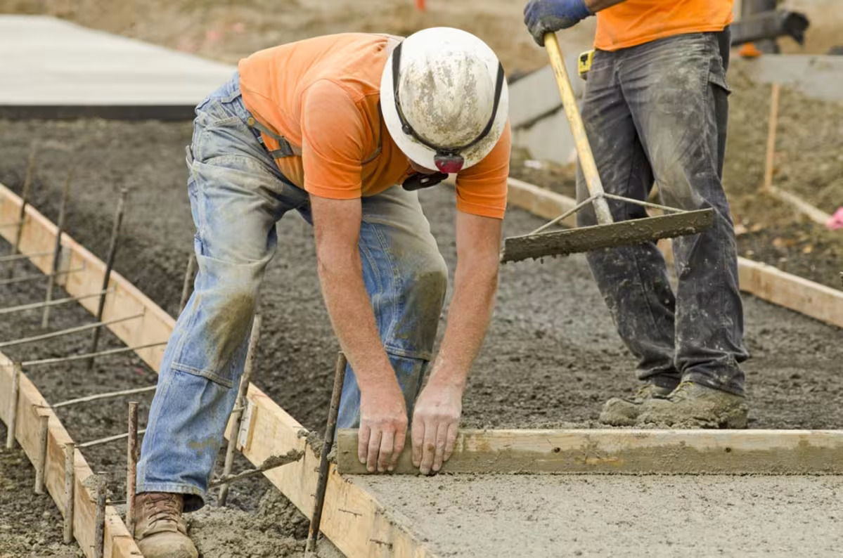 Worker hand finishing the edge of a fresh concrete slab